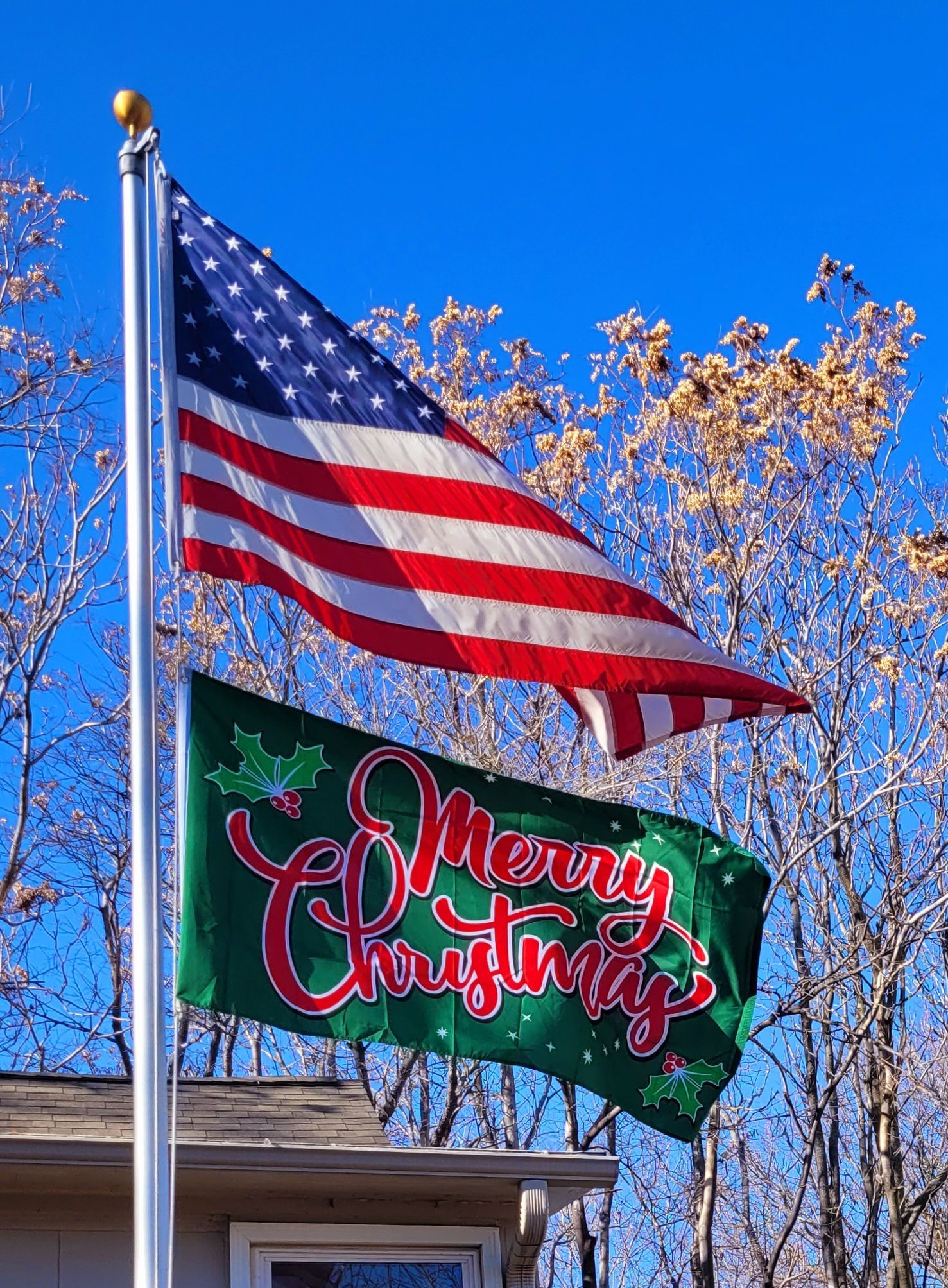 An american flag is flying next to a merry christmas flag