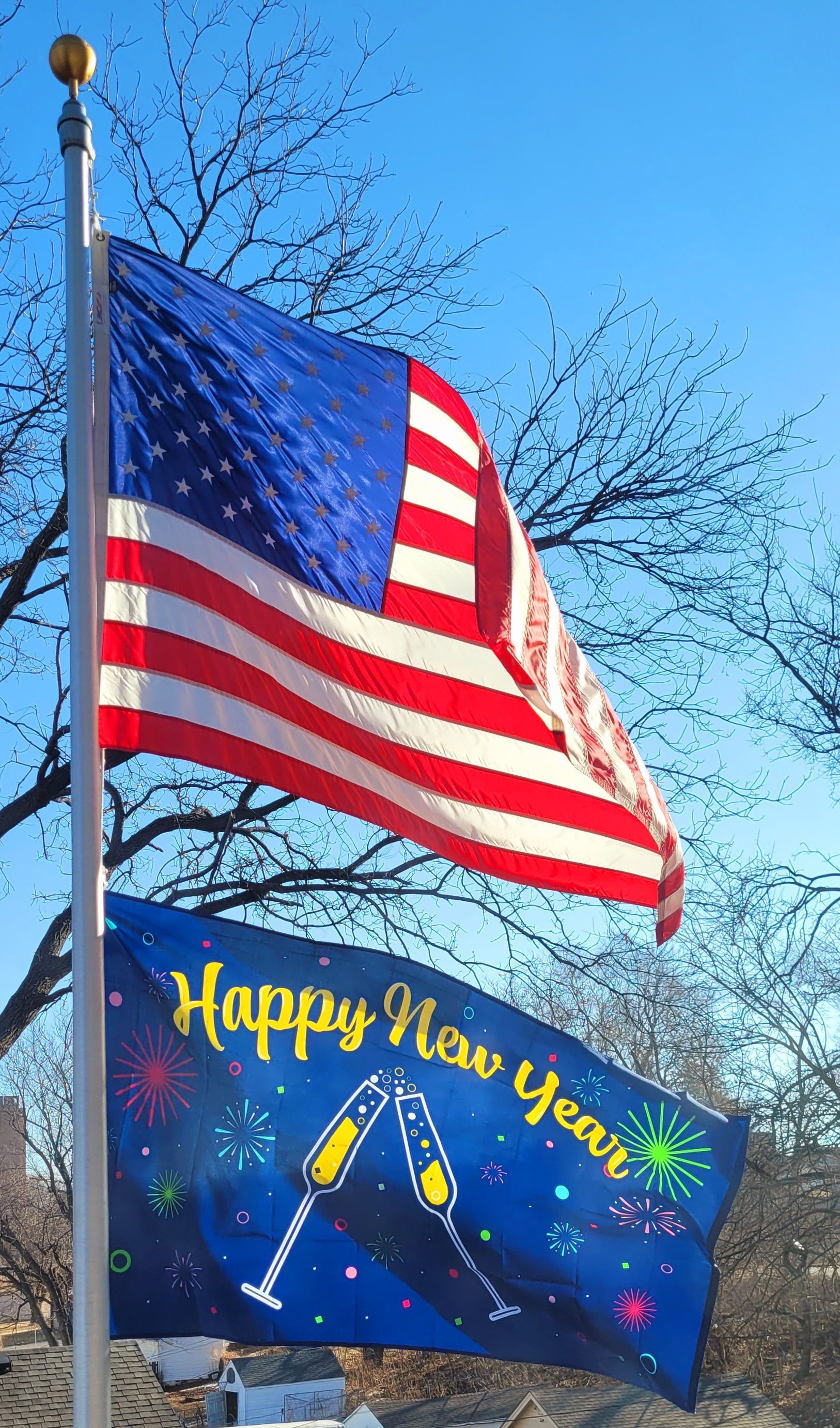 An american flag and a happy new year flag on a pole