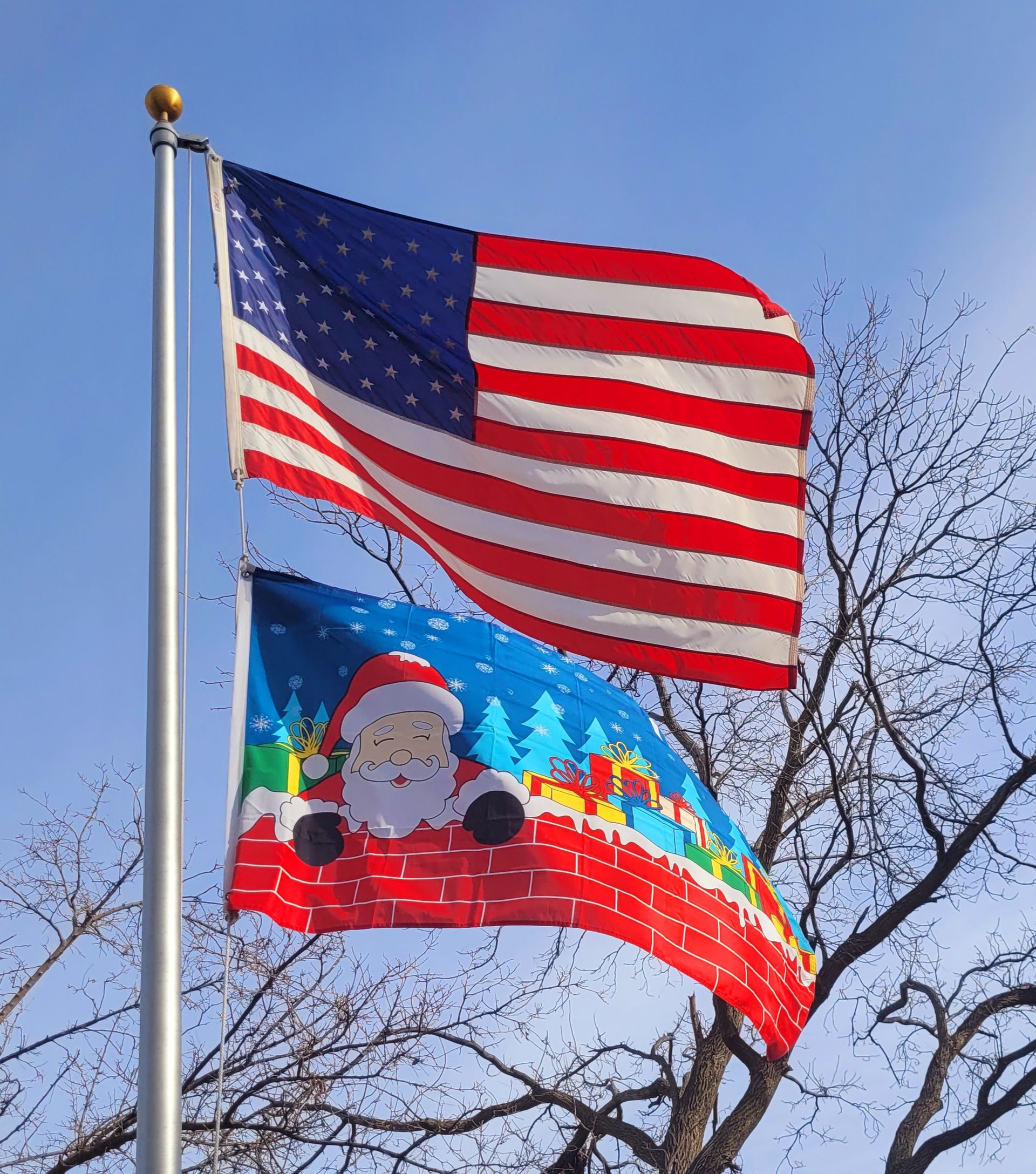 An american flag and a christmas flag are flying side by side