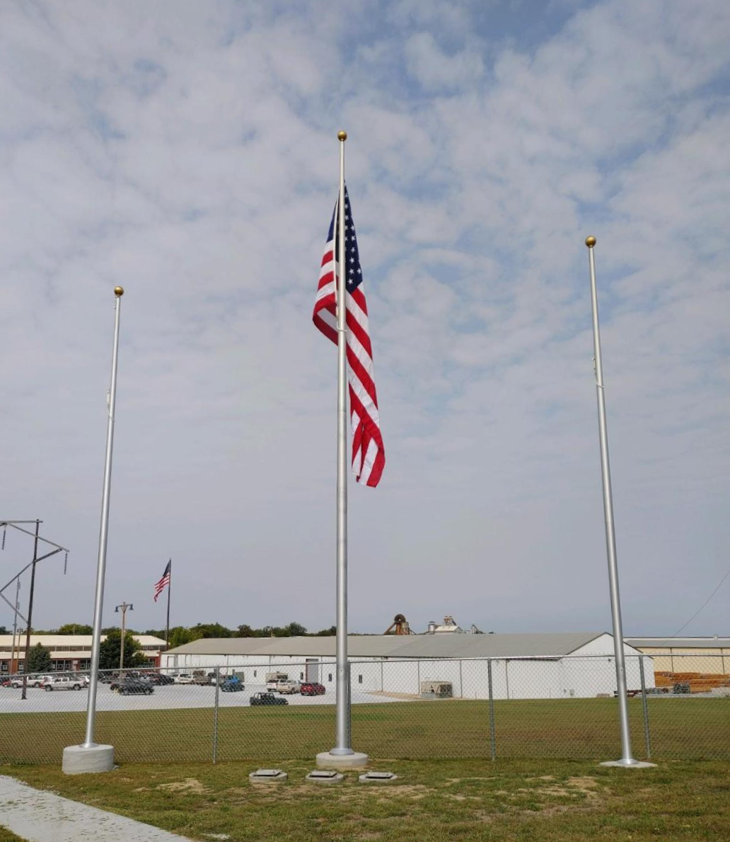 Three american flags are flying in front of a building