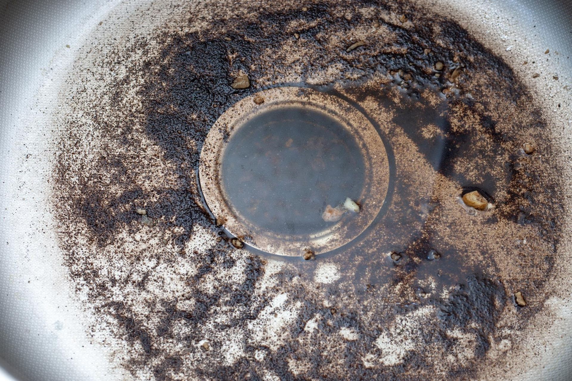 A dirty sink drain covered in black, burnt residue and debris.