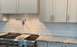 Kitchen with white cabinets, stainless steel stove, and tiled backsplash.