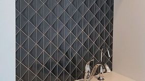 Dark diamond-patterned tile backsplash behind a silver faucet in a bathroom setting.