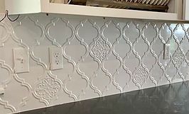 White, patterned arabesque tile backsplash with electrical outlets.