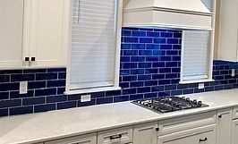Kitchen with white cabinets, blue tile backsplash, and white countertop.