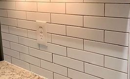 White subway tile backsplash with an electrical outlet.
