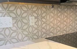 Gray and white patterned tile backsplash with electrical outlets.