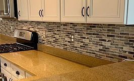 Kitchen with beige countertops, tiled backsplash, and white cabinets.