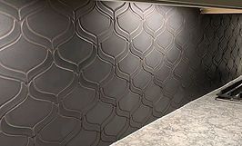 Dark gray, patterned tile backsplash in a kitchen.