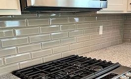 Gray subway tile backsplash above a gas stove in a kitchen.