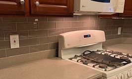 Kitchen with stovetop, grey tile backsplash, and dark cabinets.