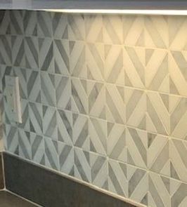 Geometric tile backsplash with light and dark gray triangles and a light.