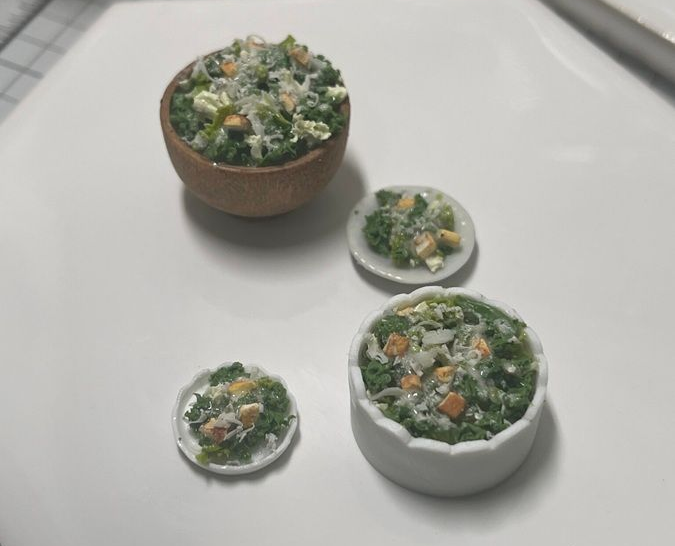 Three small bowls of green salad with vegetables on a white surface