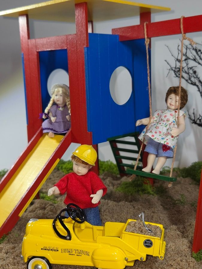 Children playing on a playground with a yellow toy car, slide, and climbing structure.