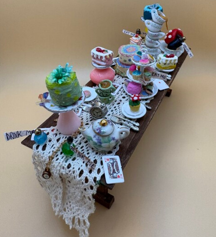 Decorative dessert display on a lace-covered table with colorful teacups, cakes, and pastries