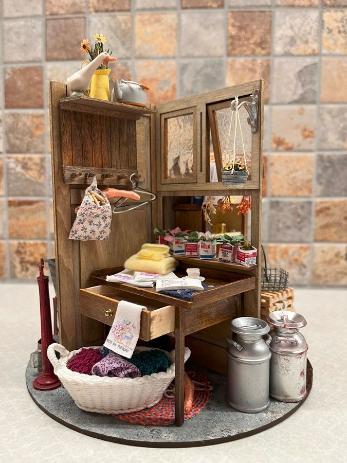 Miniature rustic market stall with shelves, jars, baskets, and small hanging goods on a round base.