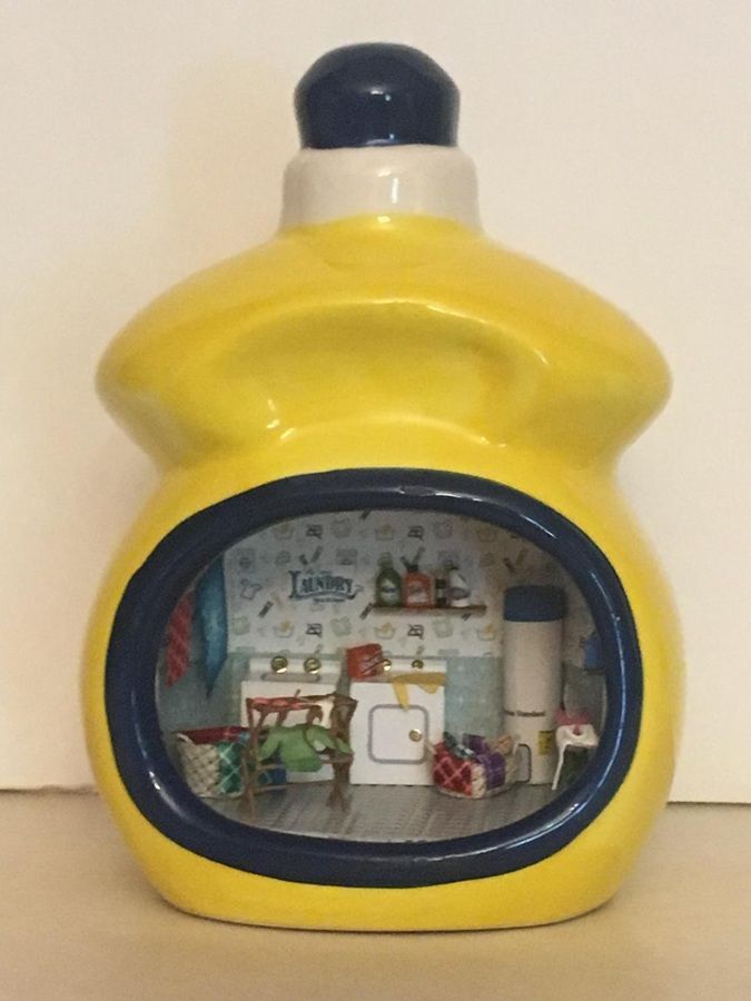 Yellow bottle-shaped ornament with a small room scene inside a round window