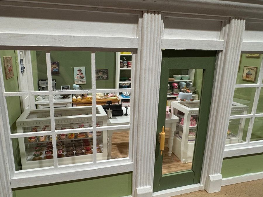 Miniature storefront with green walls, white trim, and shelves of goods inside