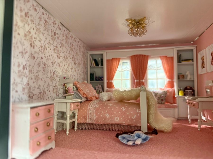 Pink floral bedroom with a bed, nightstand, vanity, and orange curtains by a bright window