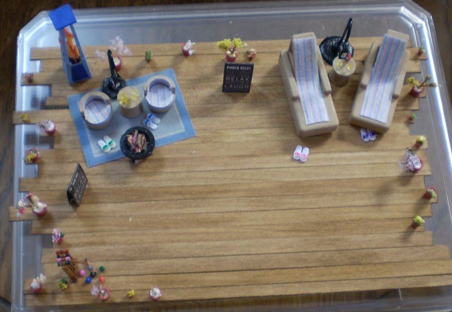 Miniature room diorama with a wood floor, blue rug, tiny furniture, and many small figures around the edges