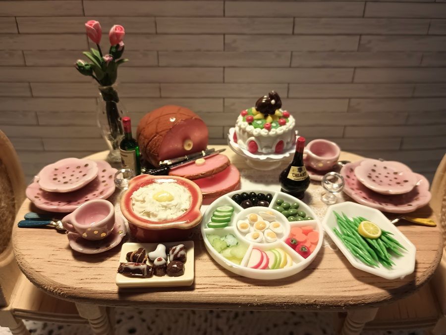 Decorated tabletop with a cake, fruit, snacks, tea set, and flowers on a wooden table