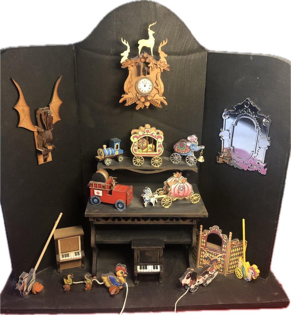 Miniature haunted house display with ornate decorations, a red toy truck, framed mirror, and tiny figures on a dark backdrop