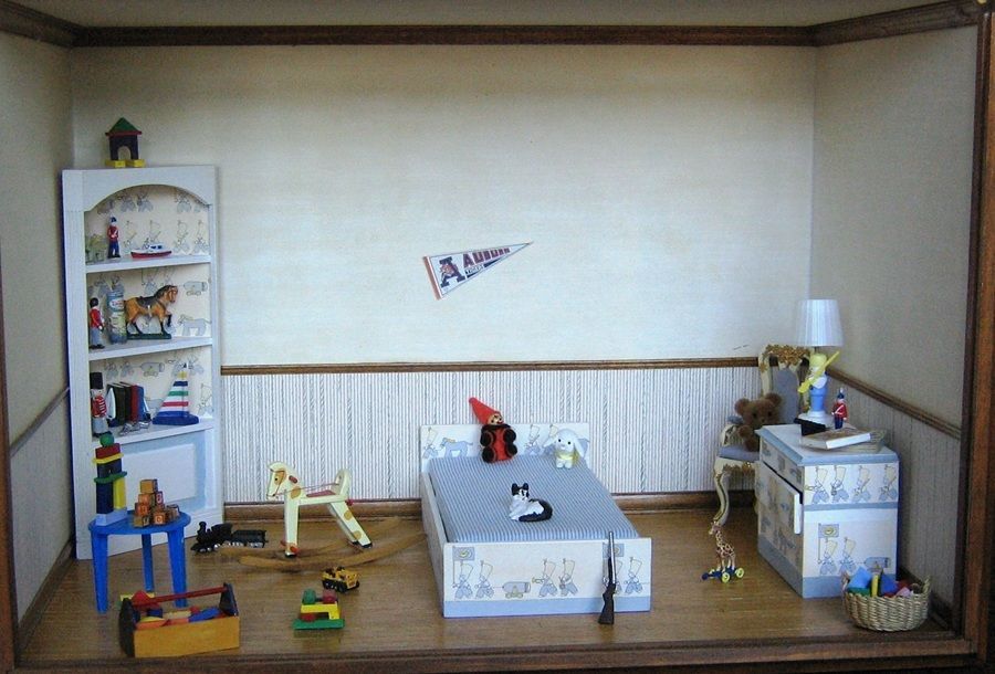 Miniature dollhouse living room with blue and white decor, toy furniture, and small figures on the floor and shelves