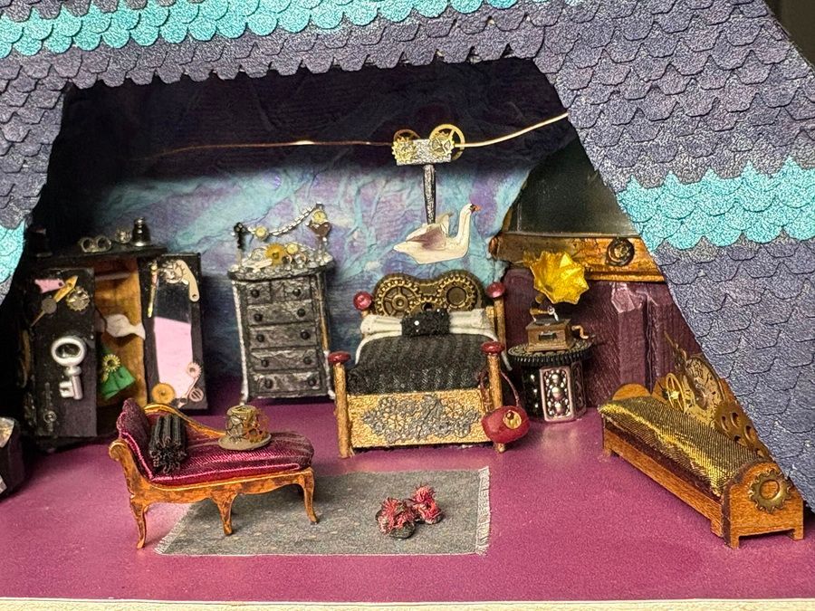 Miniature room diorama with purple floor, ornate furniture, and a decorative bed under a patterned roof.