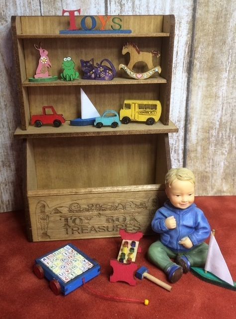 Wooden toy shelf labeled “Toys” with small cars and figurines, beside a baby doll and scattered toys on the floor