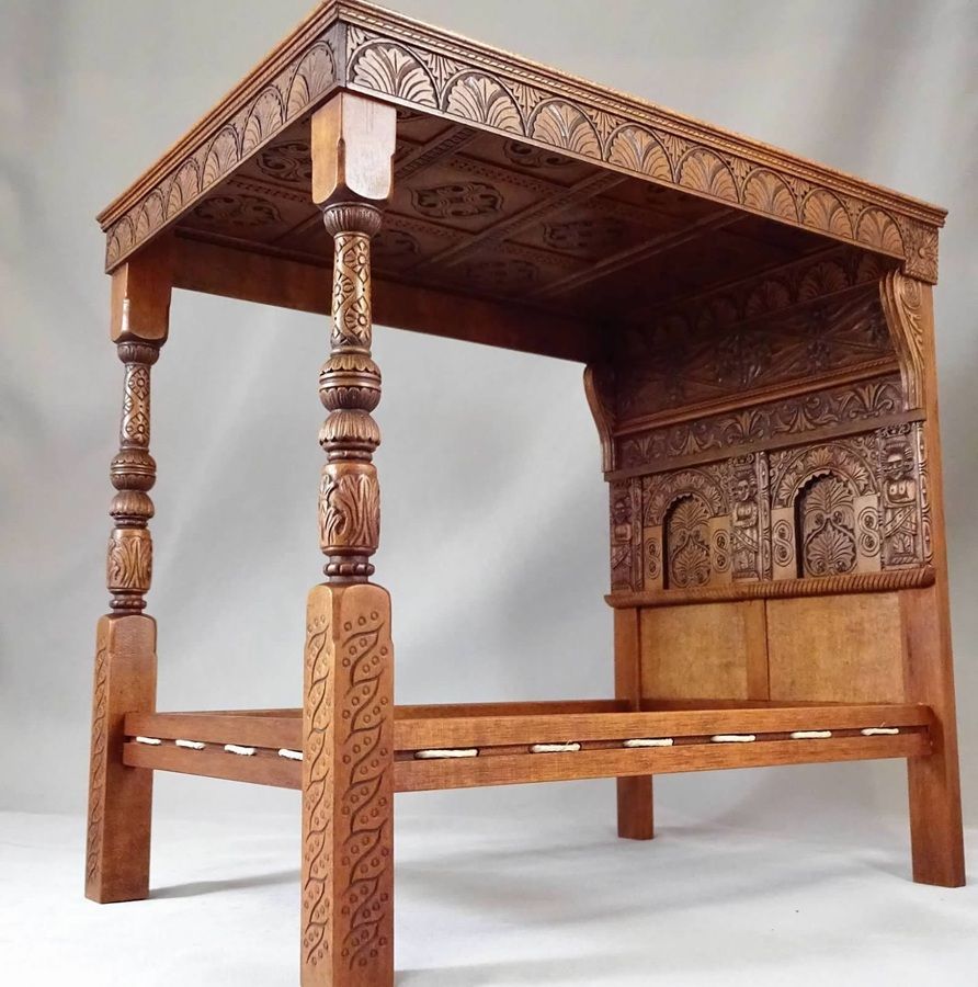 Carved wooden canopy bed with intricate details and four posts, shown against a plain background
