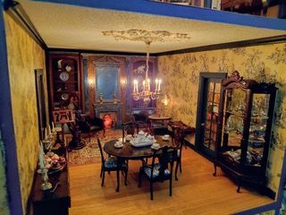 Elegant dining room with ornate dark wood cabinets, yellow wallpaper, and a chandelier over a set table.