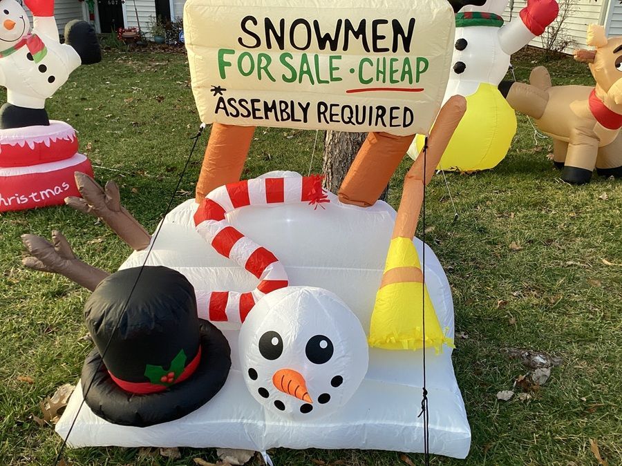 Inflatable snowman sale display with a sign reading “Snowmen for sale - cheap, assembly required.”