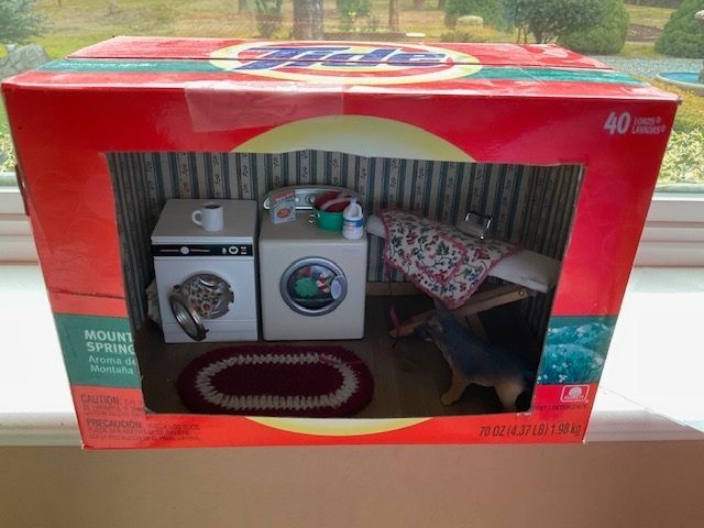 Miniature laundry room in a red box with washer, dryer, ironing board, rug, and sink