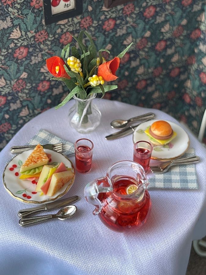 Breakfast tea setting with fruit plates, red tea glasses, eggs, and a vase of flowers on a table
