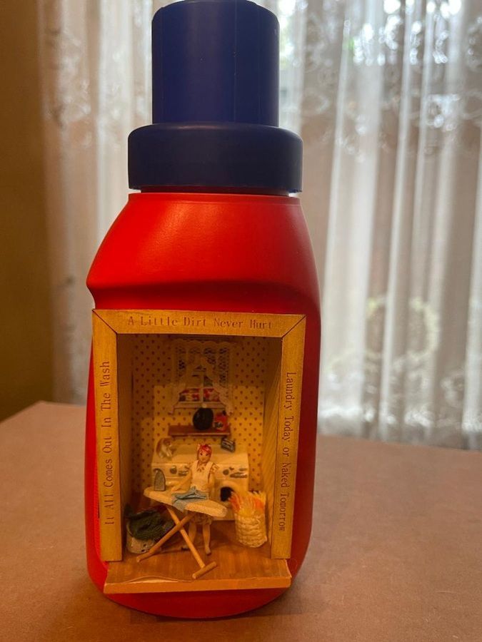 Red bottle-shaped craft with a blue cap and a small lit scene inside a cutout window.