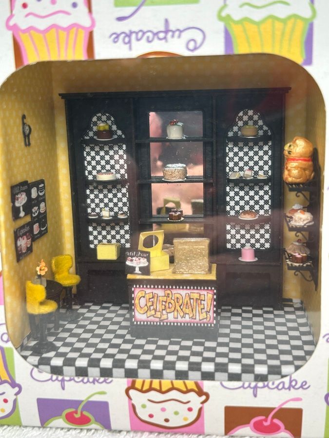 Miniature cupcake shop display with black-and-white checkered floor, pink accents, and shelves of sweets.