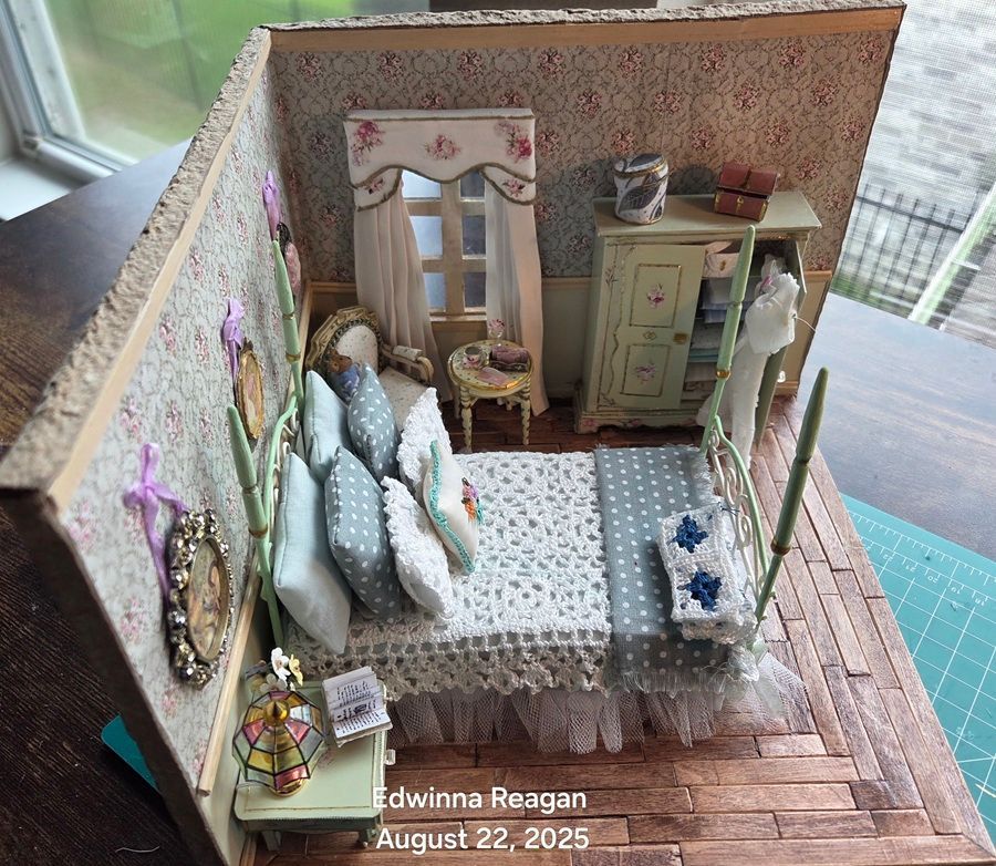 Miniature bedroom diorama with green cabinets, patterned bed, and floral walls on a wooden floor