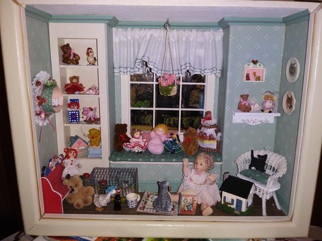 Miniature dollhouse room with window, shelves, white furniture, pink accents, and stuffed animals