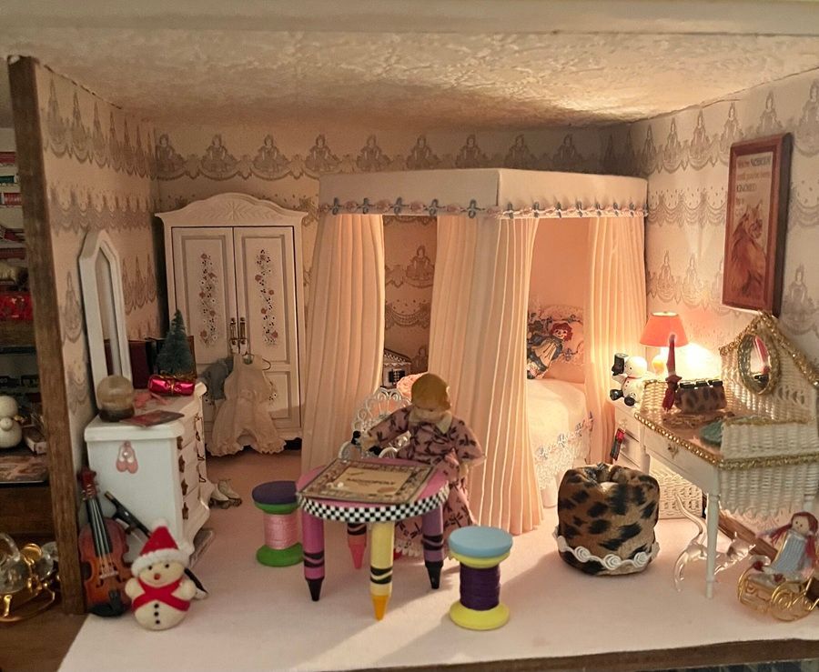 Cozy dollhouse bedroom with canopy bed, vanity, wardrobe, stool, lamp, and tiny festive decor