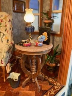 Vintage side table with a lit lamp and small figurines in a cozy, floral-decorated room