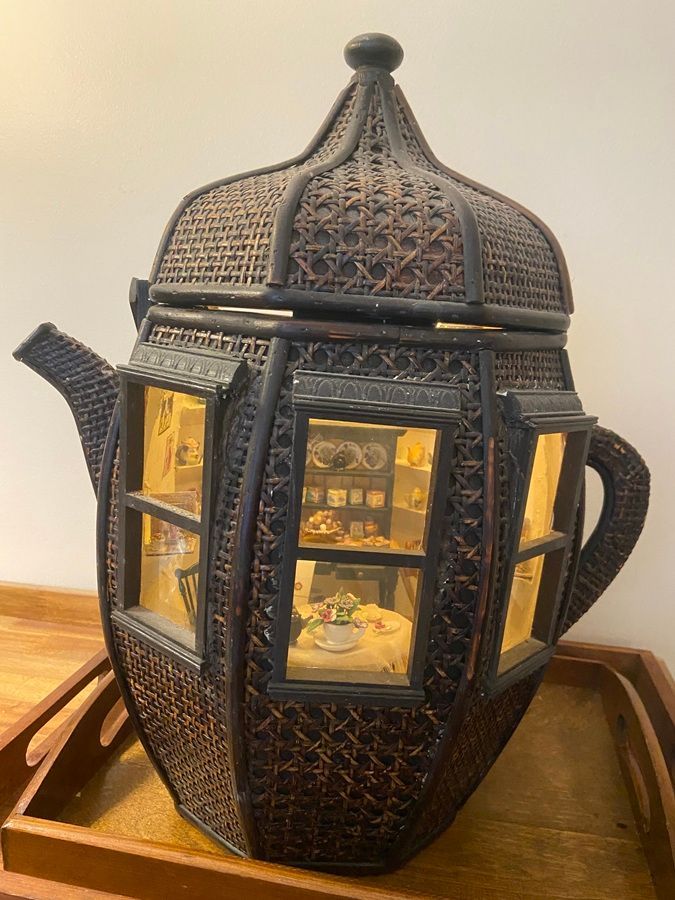 Black decorative metal lantern with warm glowing candlelight on a wooden tray