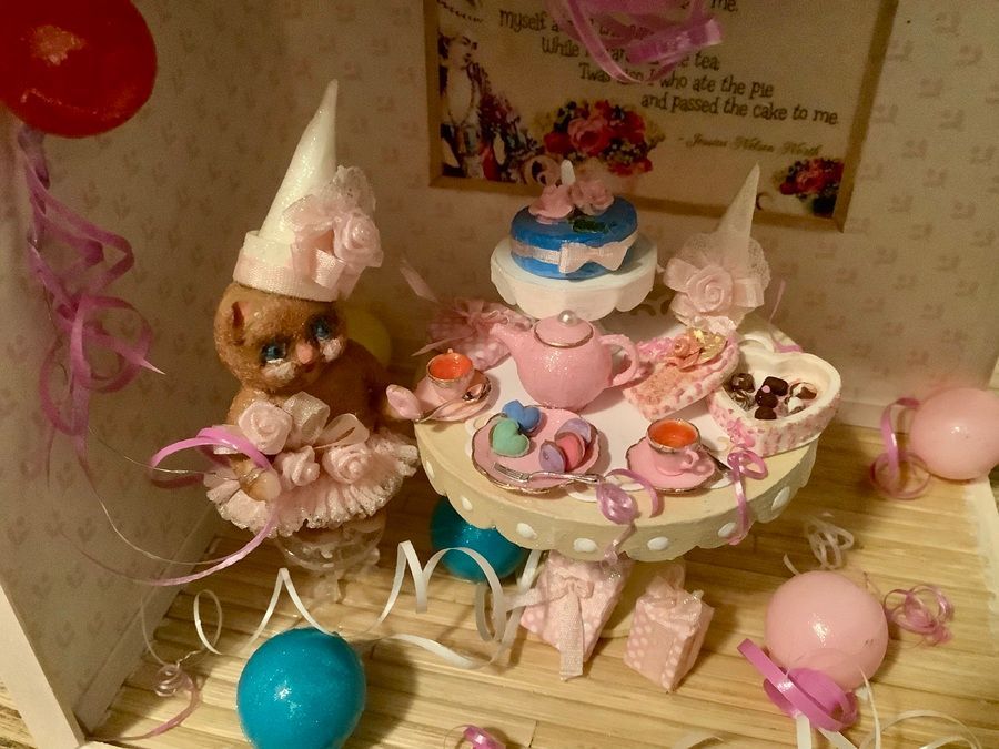 Pastel birthday party table with cakes, treats, balloons, and a doll centerpiece