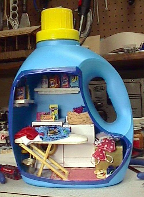 Blue toy washing machine playset with a yellow lid and tiny household items inside