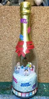 Decorated champagne bottle with a gift topper and colorful festive embellishments