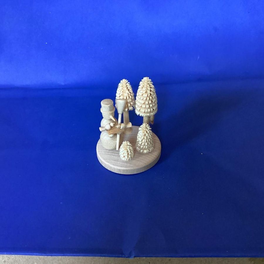 Small white ceramic figurines and trees on a round base against a blue background