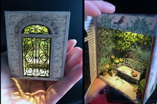 Tiny ornate dollhouse door with a glowing green arched window and a miniature room inside, held in a hand