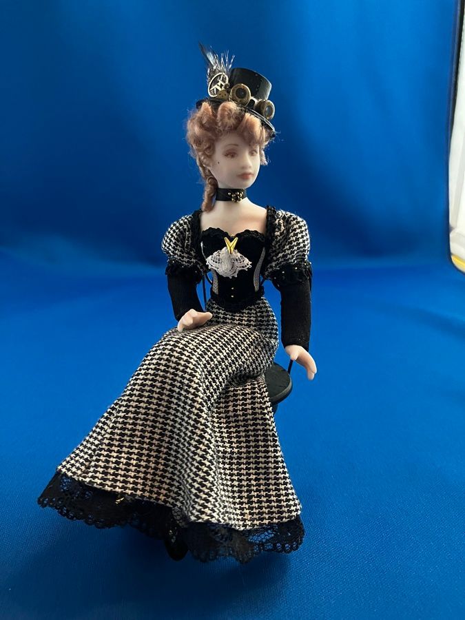 Porcelain doll in black and white checkered dress against a blue backdrop