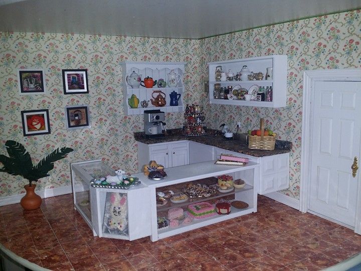 Cozy kitchen with floral wallpaper, white cabinets, tiled floor, and decorative shelves