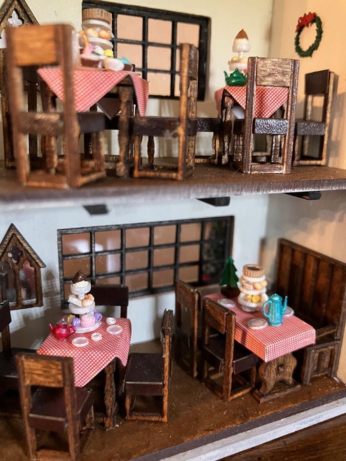 Miniature dollhouse with two dining rooms, wooden tables, chairs, and pink checkered tablecloths