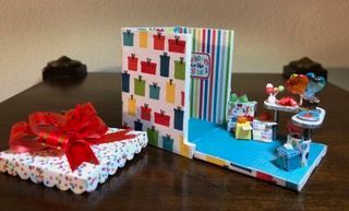 Wrapped gift boxes on a table beside a colorful handmade craft display with small decorations.